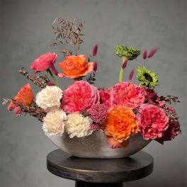 Bright mixed flower arrangement in a low silver bowl