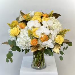 Yellow roses and white orchids in a glass vase