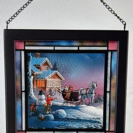 Framed winter scene with a chain hanger and a sleigh beside a snowman