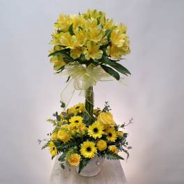 Yellow floral arrangement with roses and daisies in a white vase