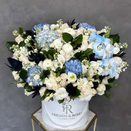 Large mixed bouquet of white, cream, and blue flowers in a white hatbox