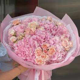 Large pink bouquet of hydrangeas and roses wrapped in pastel paper