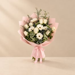 Pink-wrapped bouquet of white roses and daisies with a satin ribbon