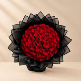 Round bouquet of red roses wrapped in black paper