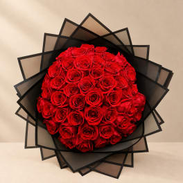 Round bouquet of red roses wrapped in black paper