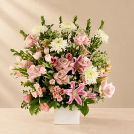 Pink roses, white chrysanthemums, and lilies in a white square vase