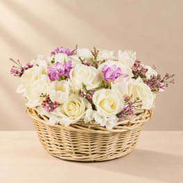 White roses and purple flowers in a wicker basket