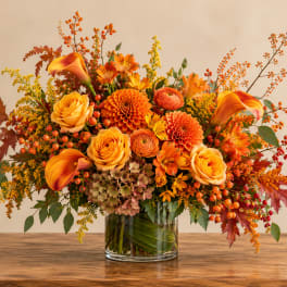 Orange and yellow floral arrangement in a clear glass vase