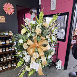 Tall standing floral spray with white and cream blooms and a gold ribbon