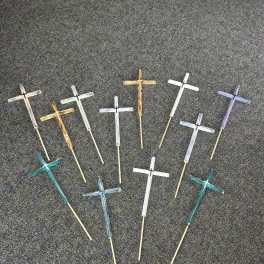 Assorted small wooden crosses on sticks arranged on a dark surface