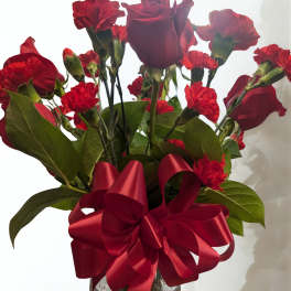 Red roses and carnations in a glass vase with a red ribbon