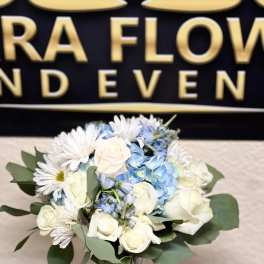 Bouquet of white roses, blue hydrangeas, and white daisies in a glass vase