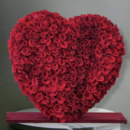 Heart-shaped arrangement of red roses on a table