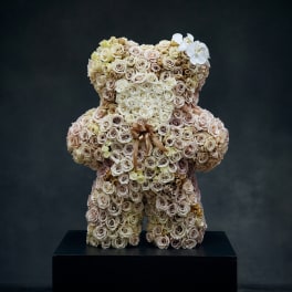 Teddy bear made of cream and blush roses with a ribbon bow