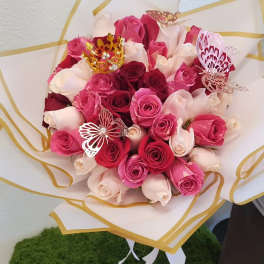 Bouquet of pink and white roses wrapped in white paper with gold trim