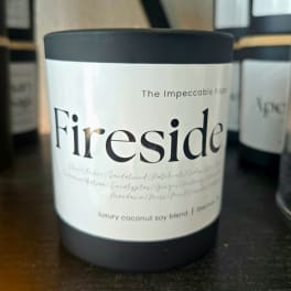 Black candle jar labeled "Fireside" on a shelf