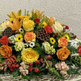 Large mixed floral arrangement with roses, lilies, and carnations in warm colors
