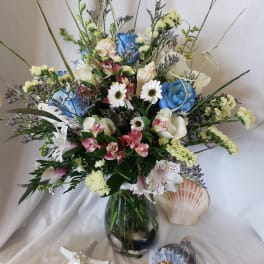 Mixed bouquet in a glass vase with blue, white, and pink flowers
