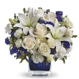 White lilies and roses arranged in a blue glass vase