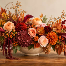 Autumn floral arrangement in a cream bowl with roses, dahlias, and orchids
