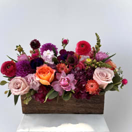Mixed bouquet in a wooden box with pink, purple, orange, and white flowers