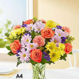 Mixed bouquet of roses, daisies, and carnations in a clear glass vase