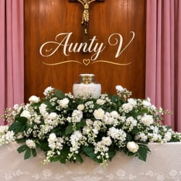 White floral arrangement with roses and small white blooms around an urn