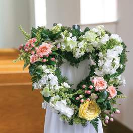 Heart-shaped floral wreath with pink, white, and yellow flowers