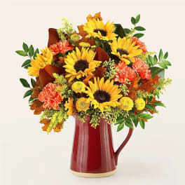 Sunflower and carnation arrangement in a red pitcher vase