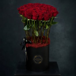 Tall box arrangement of red roses in a black cylindrical container