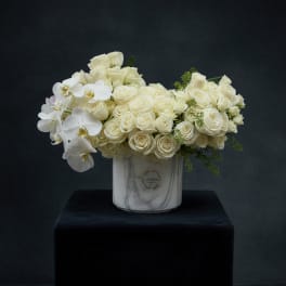 White roses and orchids arranged in a marble-look vase
