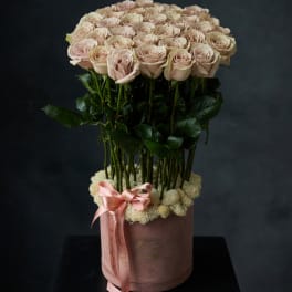 Round bouquet of pale pink roses in a pink hatbox with a ribbon