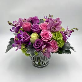 Pink and purple flower arrangement in a clear glass vase