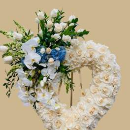 Heart-shaped floral wreath on an easel with white roses and orchids