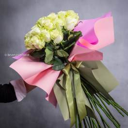 Bouquet of pale yellow roses wrapped in pink paper with a ribbon