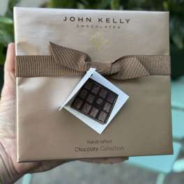 Box of assorted chocolates with a brown ribbon and gift tag