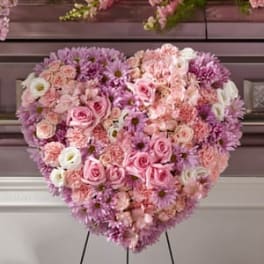 Heart-shaped floral arrangement of pink, lavender, and white blooms on an easel