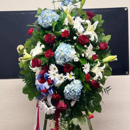 Standing floral spray with red roses, white lilies, and blue hydrangeas