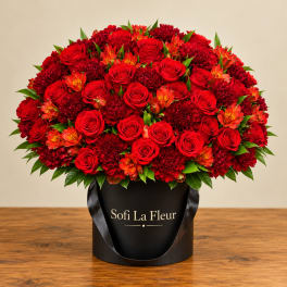 Red roses and red blooms arranged in a black hatbox with ribbon handles