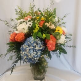 Mixed bouquet with hydrangea, roses, carnations, and daisies in a glass vase