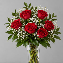 Red roses and white filler flowers in a clear glass vase