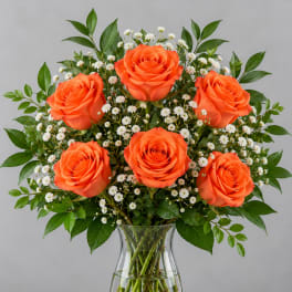 Orange roses with white baby's breath in a clear glass vase