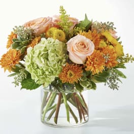 Peach roses and orange mums in a clear glass vase