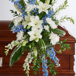 White lilies and blue flowers in a standing funeral spray