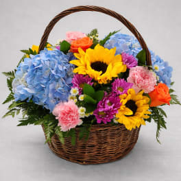 Basket of mixed flowers with sunflowers, hydrangeas, roses, and carnations