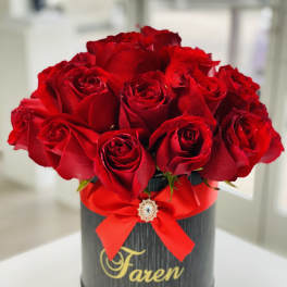 Red roses arranged in a black round box with a red ribbon