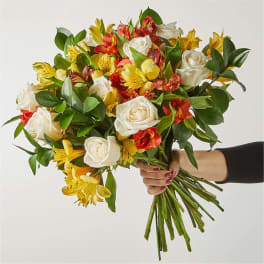 Handheld bouquet of white roses and yellow-red alstroemeria