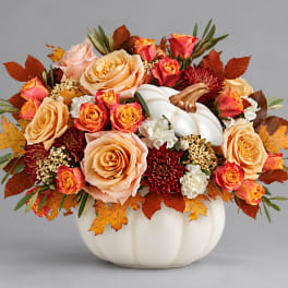 Autumn floral arrangement in a white pumpkin vase with peach and orange roses