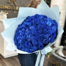 Large bouquet of vivid blue roses wrapped in pale blue paper