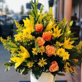 Yellow lilies and orange roses in a white vase